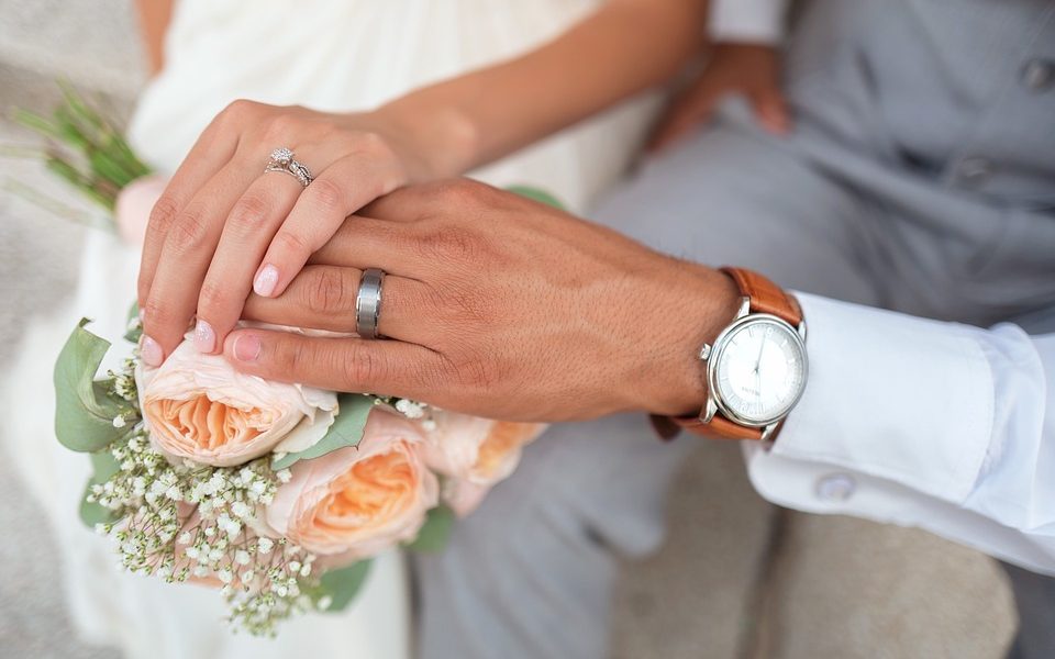 Pareja en boda agarrándose la mano sobre ramo