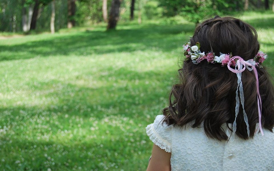 Plano de niña vestida para boda mirando al horizonte en el campo