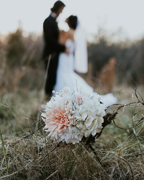 Personas casándose en un campo enfocando a flor
