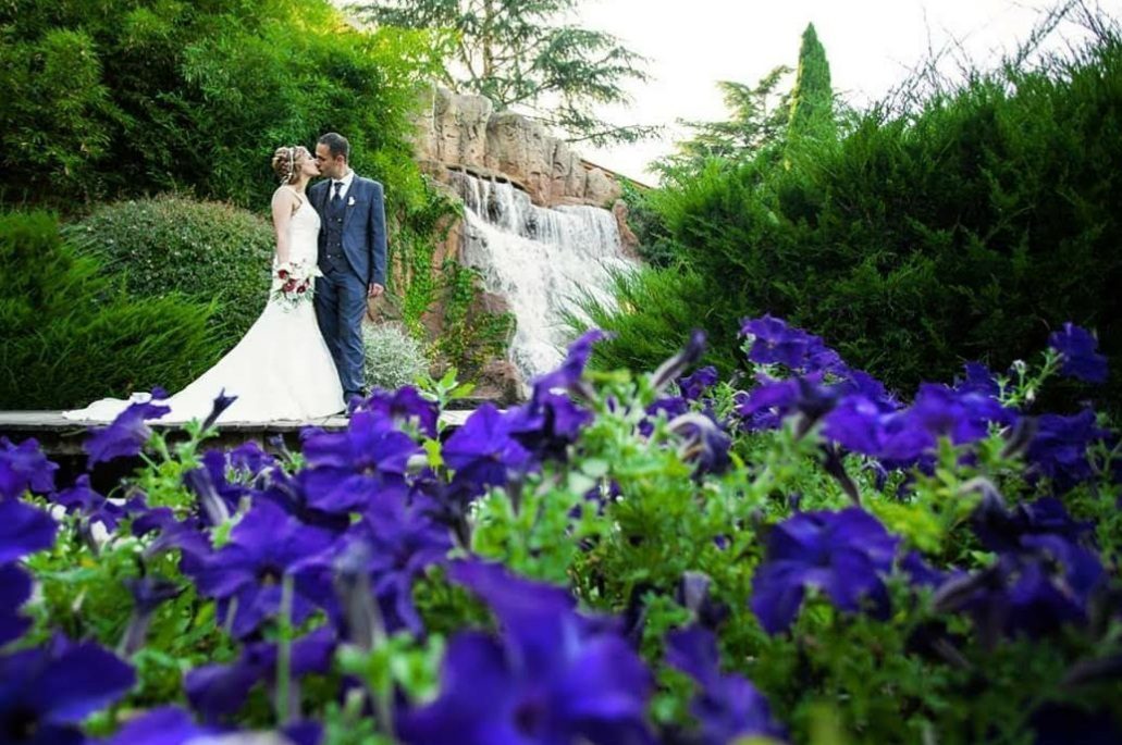 Pareja besándose en la boda en exterior con plantas y flores