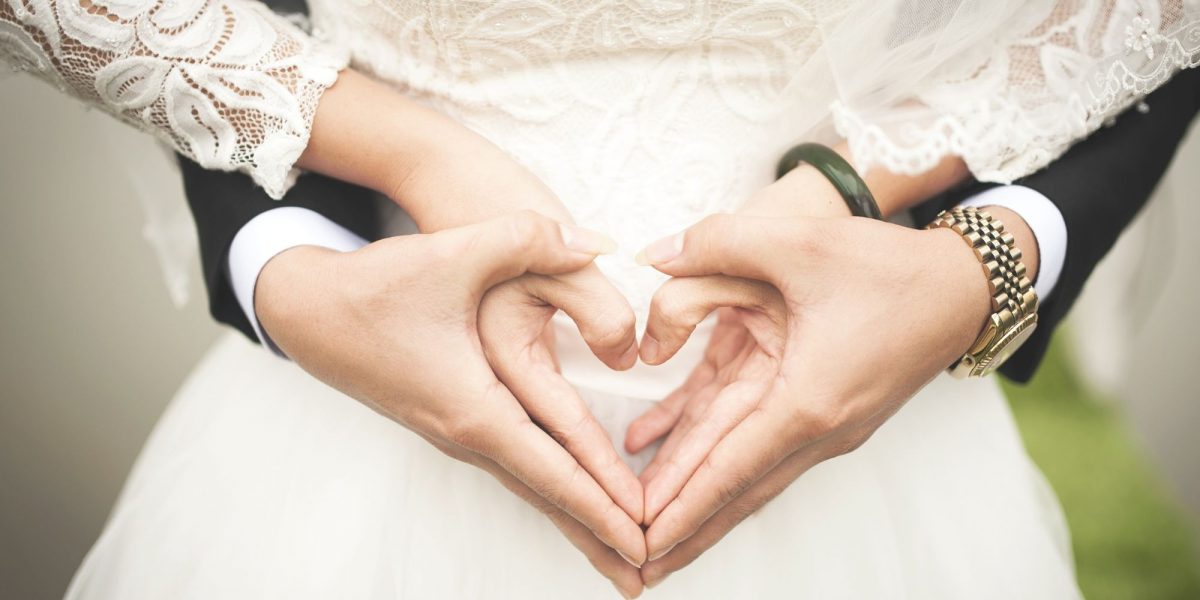 Pareja pone las manos en forma de corazón